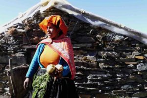 A mother proudly presents veggies from her greenhouse